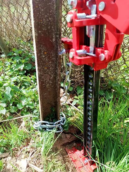 Close-up of a farm jack that was pulling on a fence post (actually a thick steel U profile). The chain has parted and one link dangles open.
