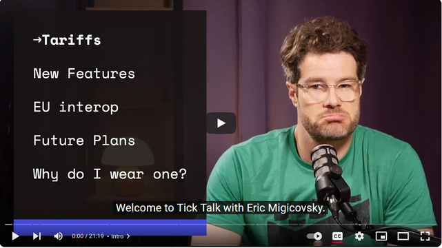Screengrab of YouTube video thumbnail, featuring a male-presenting person on the right side of the frame; he has curly auburn hair, scruffy short beard, and spectacles with clear plastic frames. He is wearing a green T-shirt with a black silhouette of a LEGO brick, and a performatively sad expression.

Text on the left side reads as follows:
-> Tariffs
New Features
EU interop
Future Plans
Why do I wear one?

Centered caption at the bottom of the frame reads "Welcome to Tick Talk with Eric Migicovsky."