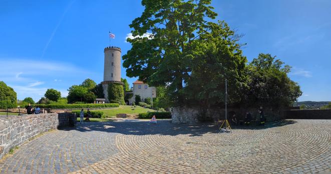 Panoramabild der Einsatzstelle mit Sparrenburgturm. blauer Himmel, satt grün belaubte Bäume.