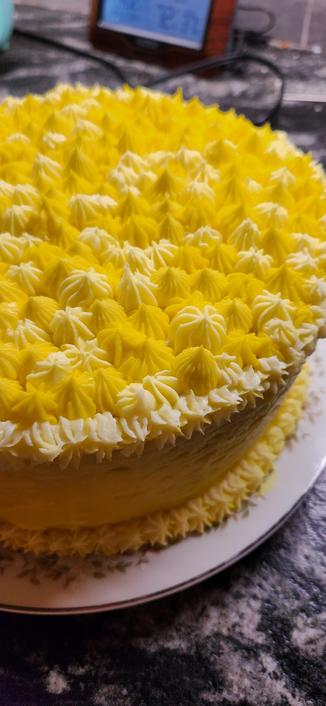 Close up of a round cake with frosted stars of various sizes and shapes, all in different shades of yellow.