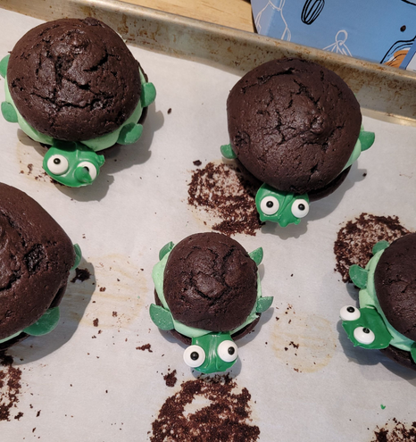 Chocolate whoopee pies decorated to look like turtles with green chocolate heads and flippers, sugar eyes, and green butter cream filling.