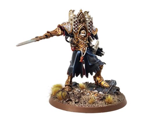 Photo of a Games Workshop Morvenn Vahl miniature - a figure in giant, baroque, golden armour wielding a spear and gun/shield combo - standing amongst a ruined battlefield.