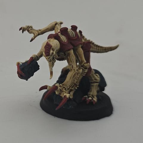 A warhammer 40k genestealer painted in bone and red.