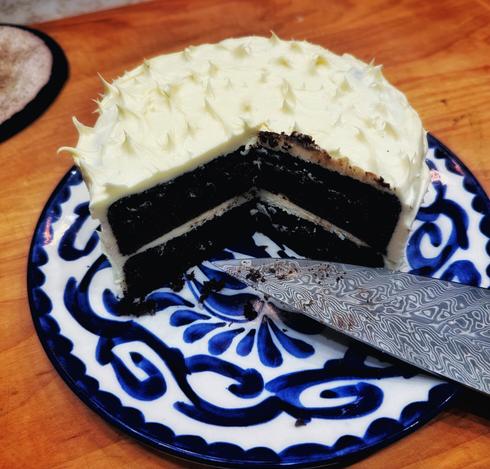 Cut chocolate cake on plate with knife.