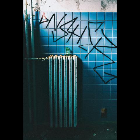 In an abandoned sanatorium, just a radiator  with a broken bottle above.On the wall , blue tiles
