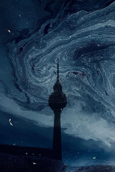 Fernsehturm spiegelt sich in einer Pfütze, auf der sich Blütenstaub dreht.