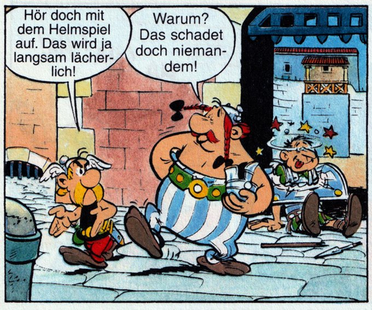 Asterix und Obelix gehen durch die Stadt, Obelix hat einen Legionär niedergeschlagen und seinen Helm genommen. Der Legionär liegt hinter den beiden Galliern auf dem Boden und sieht Sterne.