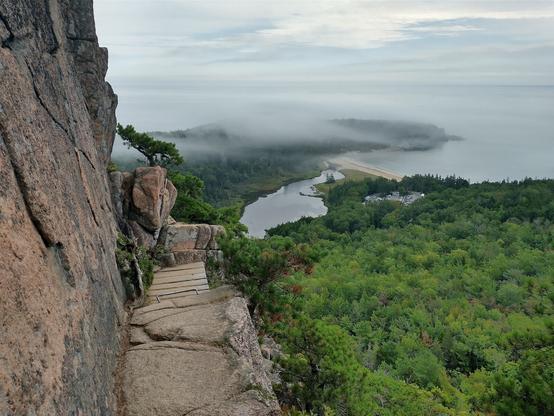 Narrow rocky mountain path. A granite cliff on the left and a dramatic fall to your death is on the right. A foggy Atlantic Ocean is visible too.