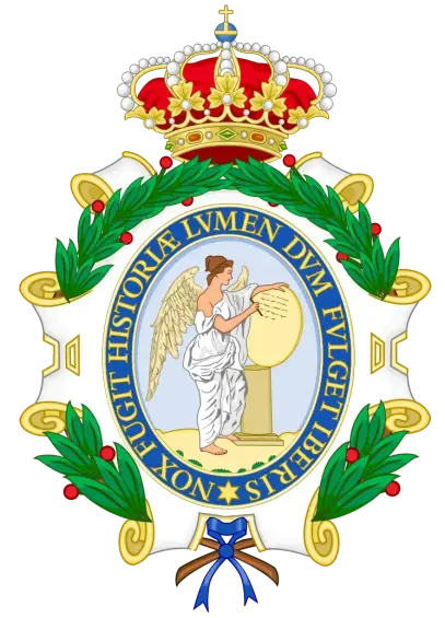 The image depicts a coat of arms, which typically features various symbolic elements. In this case, it includes an angel holding a tablet, surrounded by a floral wreath and a crown at the top. The text in Latin reads "FUGIT HISTORIA LVMEN DVM FVLGET LIBERTAS NOX" which can be translated to refer to themes of history, freedom, and possibly light. This coat of arms appears to represent a specific organization or institution.

Image Credits: Wikimedia / Heralder / CC BY-SA 3.0