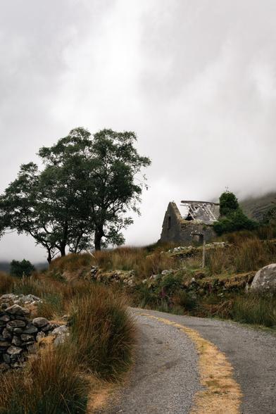 a road leading to an abandoned building on a hillside