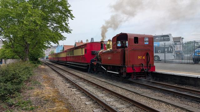 A steam train with engine no. 4 about to pull backwards, there are red and cream carriages making up the train