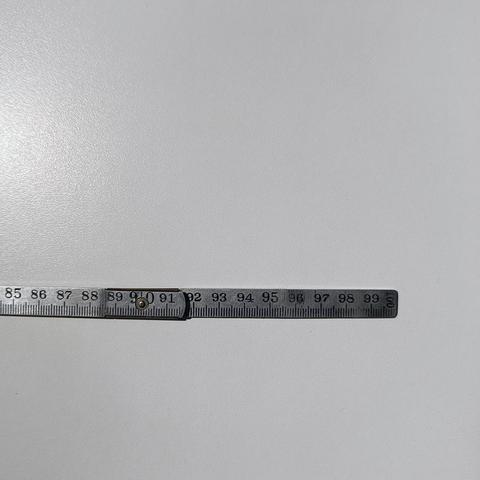 A folding metre rule made of grey metal with black lettering on a white surface.