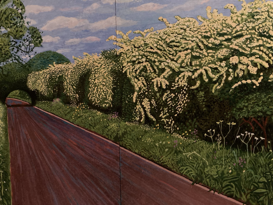 Painting by David Hockney. You see a redbrown diagonally area  on the left which is a road, flanked by green grass mixed with white flowers. In the middle an area with worm-like structures suggesting the twining branches of Hawthorn, loaded with blossom. On top blue sky with white clouds.