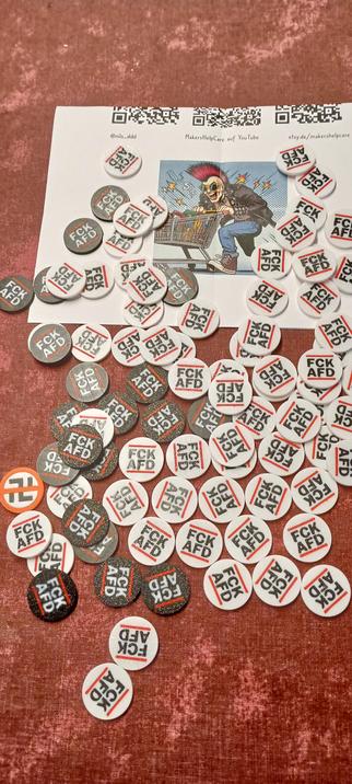 Einkaufswagenchips mit dem Aufdruck FCKAFD in schwarz und weiß. Ca. 100 Stück, liegend auf dem Tisch fotografiert.