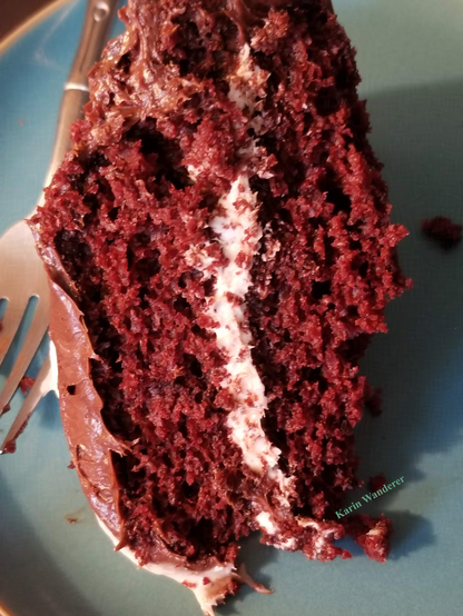 Photo of a slice of chocolate-frosted chocolate layer cake, with vanilla frosting between the layers. Someone took a few bites before taking the picture!