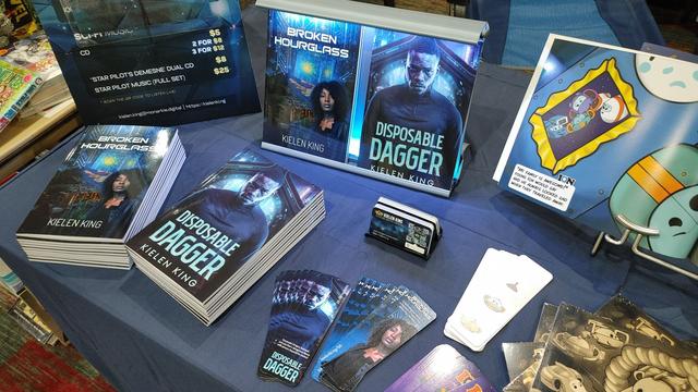 Convention table set up with books, bookmarks, and business cards for sale