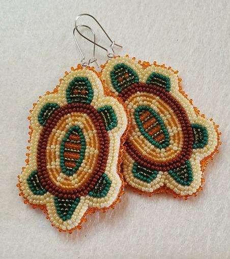 a pair of beaded earrings by kiamichi of turtles with brown shells and dark green bodies