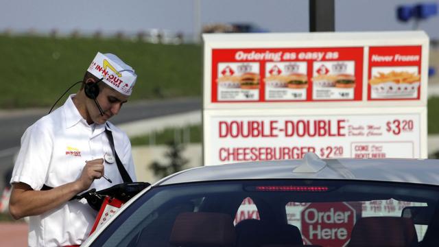 An In-N-Out Burger employee takes a drive-thru order.