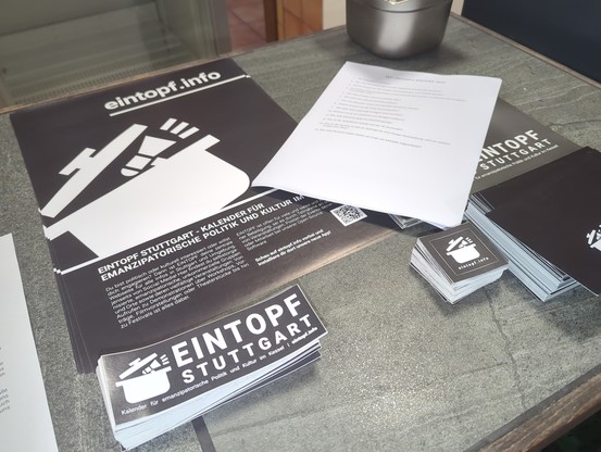Werbematerial für EINTOPF liegt auf einem Tisch: Plakate, Flyer und Aufkleber