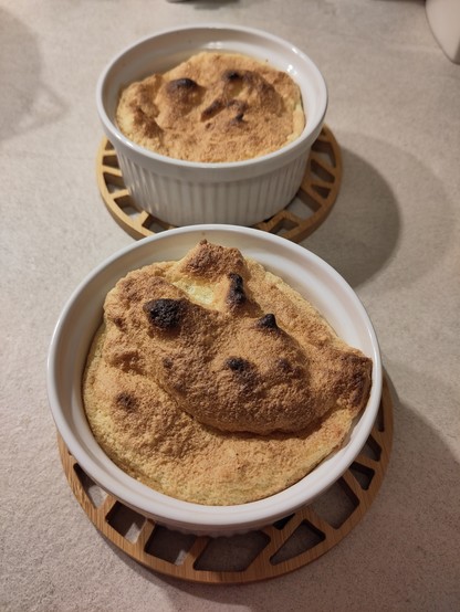 Zwei kleine weiße Keramikformen mit je einer Salzburger Nocke aus Eischnee, ein wenig Eigelb, Zucker und Speisestärke 