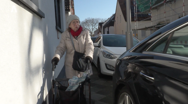 Eine Frau mit Rollator versucht in Mannheim den Gehweg zu benutzen. Dieser ist durch parkende Kfz soweit verengt, dass kaum ein Durchkommen ist und sie regelmäßig auf die Straße ausweichen muss.