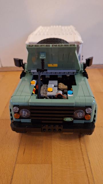 Das Bild zeigt ein Lego-Modell eines Land Rover Defender, das auf einem Holzboden steht. Die Motorhaube des Modells ist geöffnet und gibt den Blick frei auf den detaillierten Motorraum, der ebenfalls aus Lego-Steinen besteht. Die Karosserie des Land Rovers ist in einem hellen Grünton gehalten, und auf der Motorhaube ist der Schriftzug "DEFENDER" zu sehen. Vorne sind die typischen runden Scheinwerfer und das Land Rover-Emblem erkennbar. Im Hintergrund ist eine weiße Wand zu sehen.

Bereitgestellt von @altbot, generiert mit Gemini