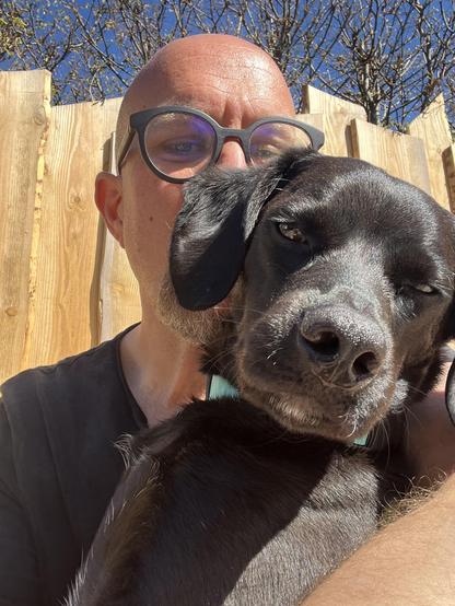 Ein Mann mit rasiertem Kopf und Brille hält einen schwarzen Labrador Retriever in seinen Armen. Der Hund hat ein glänzendes, glattes Fell und schaut direkt in die Kamera, während er seinen Kopf an den Mann lehnt. Der Mann trägt ein dunkles T-Shirt und hat einen kurzen Bart. Im Hintergrund ist ein Holzzaun und ein blauer Himmel mit kahlen Bäumen zu sehen. Die Szene wirkt freundlich und entspannt, mit Sonnenlicht, das die Szene beleuchtet.

Bereitgestellt von @altbot, privat und lokal generiert mit Ovis2-8B

🌱 Energieverbrauch: 0.171 Wh