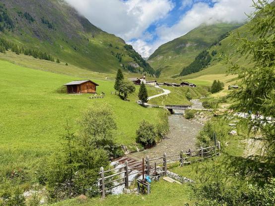 Berglandschaft mit Bach und Holzhäusern im Valsertal – die Alpe Fane