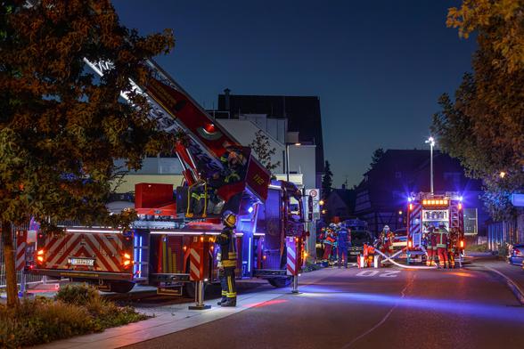 Eine Drehleiter und ein Löschfahrzeug der Feuerwehr bei einer Übung nach Einbruch der Dunkelheit