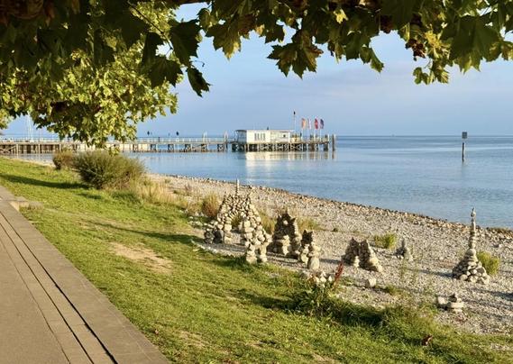 Der Bodensee bei Hagnau mit Schiffsanleger und mit kunstvollen Steinmännchen im Vordergrund 