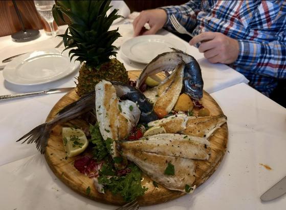 Eine Holzplatte mit Fisch und Ananas 